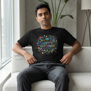 Man wearing black t-shirt with colorful gamer-themed Happy Birthday graphic, sitting on a couch.