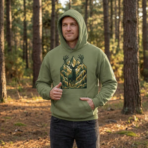 Man wearing green hoodie with stag and mountain graphic, standing in a sunlit forest