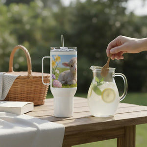 Easter tumbler with lamb and flowers on picnic table beside lemonade pitcher and wicker basket