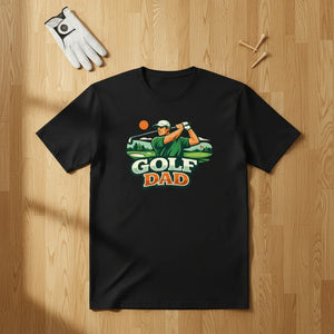 Black Golf Dad t-shirt with golfer graphic, laid flat on wood floor with glove and tees.