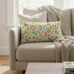 Floral decorative throw pillow with birds and butterflies on a beige sofa in a cozy living room