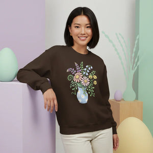 Woman wearing brown sweatshirt with pastel floral vase graphic, spring home decor setting