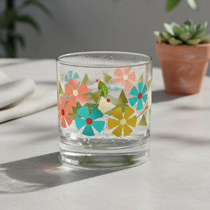 Colorful floral-patterned glass tumbler with sparkling drink on a light table, succulent in background