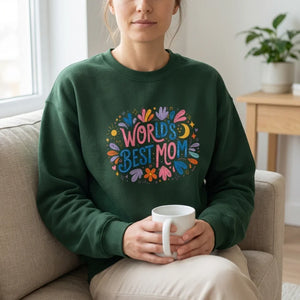 Woman wearing green World's Best Mom sweatshirt holding a mug on a couch