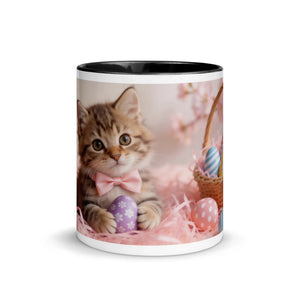 White ceramic mug with black interior, featuring a kitten in a pink bow tie holding a decorated Easter egg, with a basket of colorful eggs and pink decorative grass.