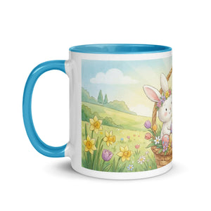 White ceramic mug with blue handle and rim, featuring a cute bunny in a spring flower field illustration
