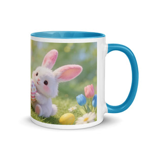 White ceramic mug with blue handle, featuring cute bunny with Easter eggs and spring flowers.