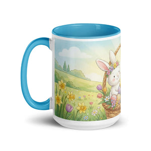 White ceramic mug with blue handle and interior, featuring a cute bunny with flowers and Easter eggs in a spring meadow illustration.