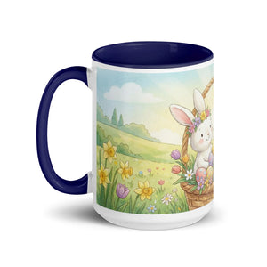 White ceramic mug with dark blue handle and rim, featuring a cute bunny in a spring meadow with flowers.