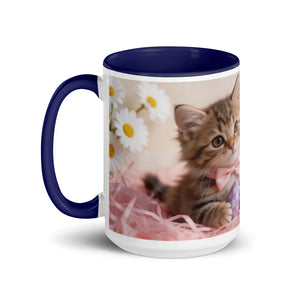 White ceramic mug with dark blue handle and rim, featuring a kitten, daisies, and pink ribbon.