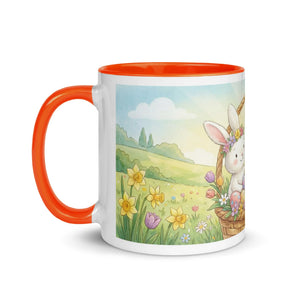 White ceramic mug with orange handle and rim, featuring a cute bunny in a basket with spring flowers.