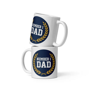 Stacked white ceramic mugs with blue and gold 'Number 1 Dad' design on white background