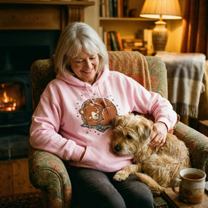 Older woman in cozy pink bear hoodie relaxing with dog by fireplace, warm home setting