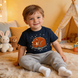 Smiling toddler boy in a cozy room, wearing a navy t-shirt with a cute bear print