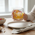 Hand holding floral Happy Mother's Day glass of orange juice at breakfast table
