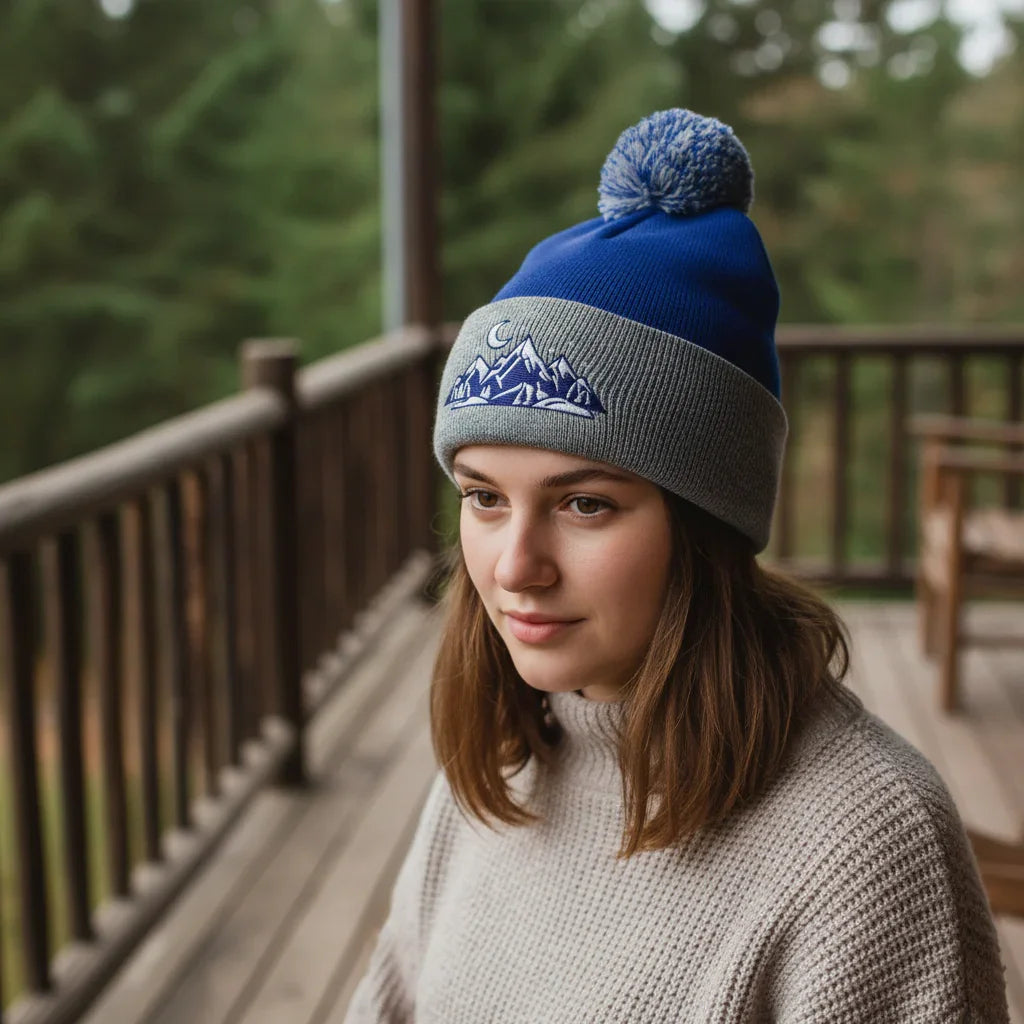 Woman in cozy knit sweater and blue mountain pom beanie on wooden porch outdoors