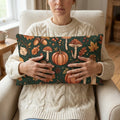 Woman holding decorative pillow with autumn-themed pumpkins, mushrooms, and leaves pattern