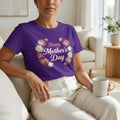 Woman in purple 'Happy Mother's Day' floral t-shirt sitting on sofa holding coffee mug