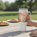 Easter-themed travel mug with bunny and chick design, outdoor picnic setting, pastries nearby