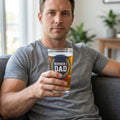 Man holding a pint glass with Number 1 Dad design, sitting on a sofa with beer