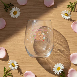 Mother's Day glass with bear illustration, surrounded by daisies and flower petals on wood table