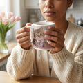 Woman holding a cute kitten mug with pink bow in cozy kitchen, steaming coffee inside
