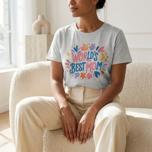Woman wearing gray t-shirt with colorful 'World’s Best Mom' floral graphic, sitting indoors