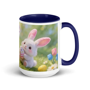 White ceramic mug with dark blue handle, featuring a cute bunny holding a painted Easter egg, flowers in background.