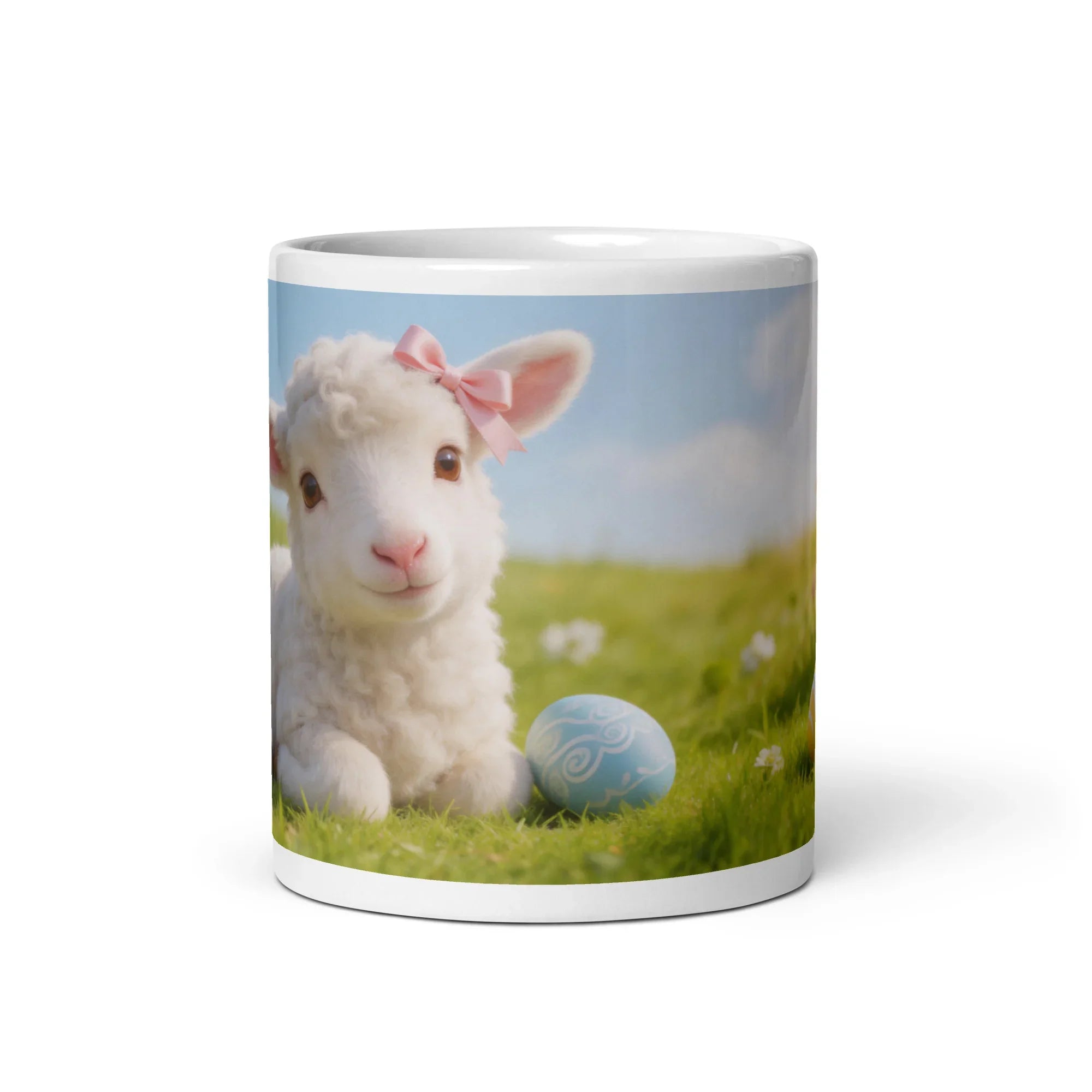 White ceramic mug featuring a cute lamb with a pink bow and an Easter egg on green grass